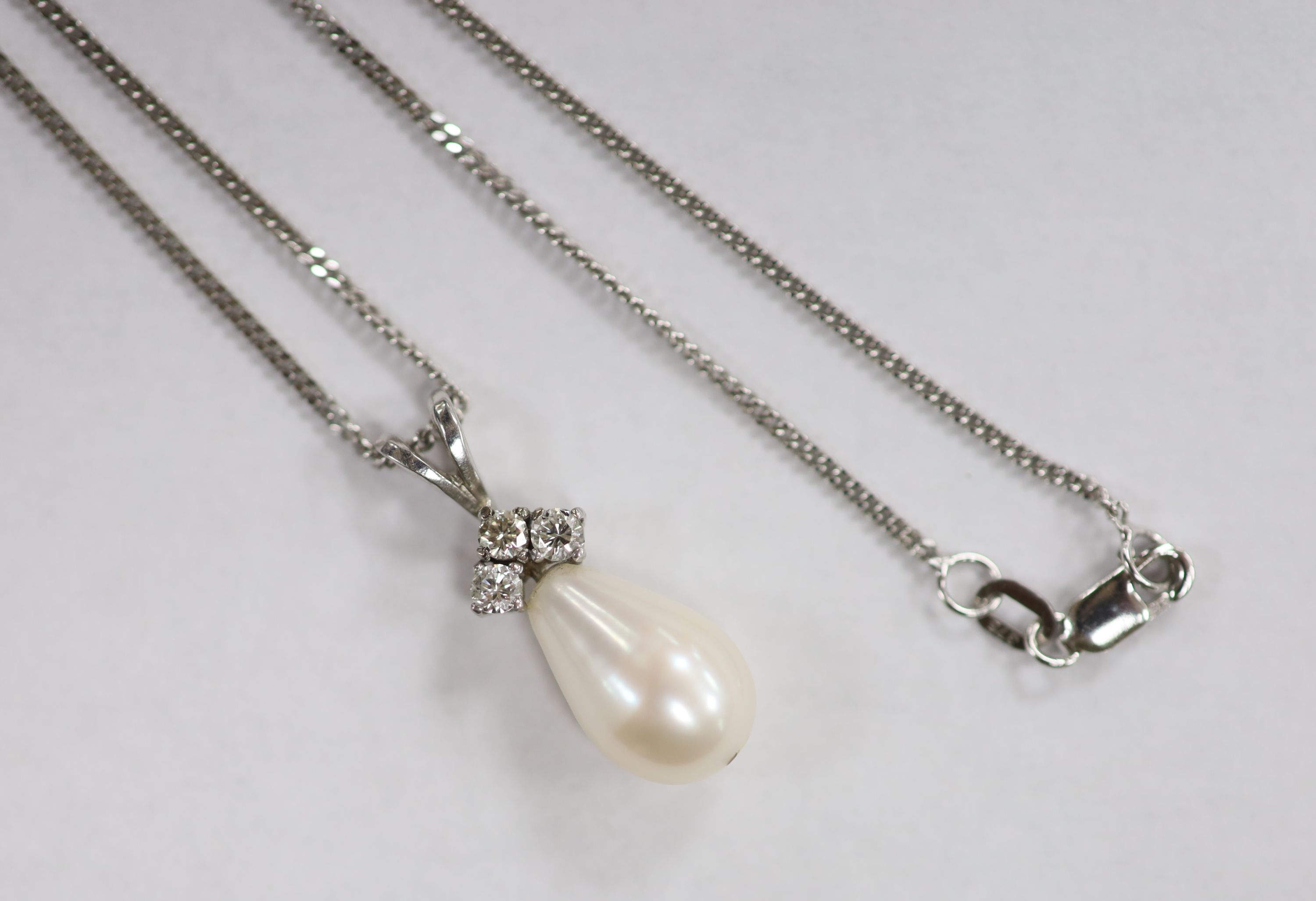 A modern 18ct white gold, cultured pearls and three stone diamond set pendant, 24mm, gross 2.4 grams, on a 9ct white gold fine link chain, 44cm, 3.1 grams.